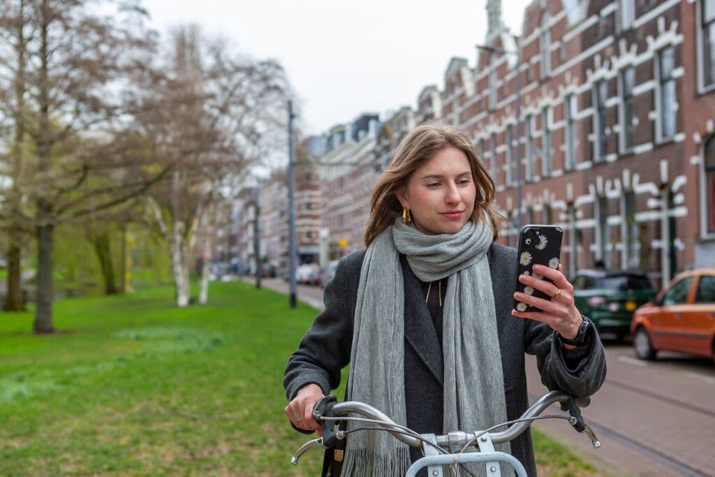 Vrouw op fiets kijkt op mobiele telefoon in de herfst